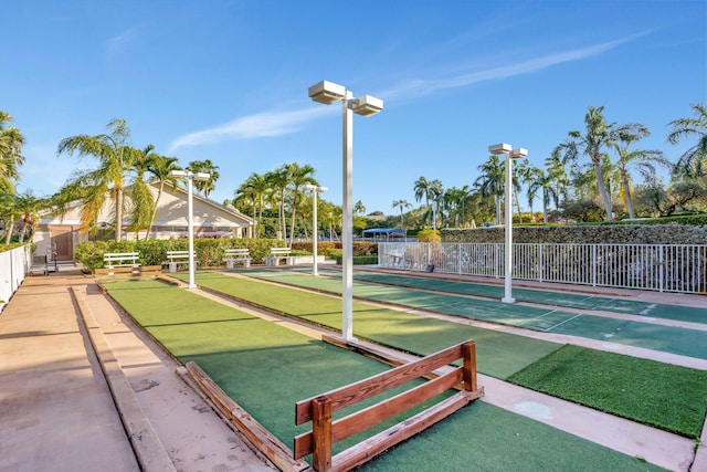 view of community with fence and shuffleboard