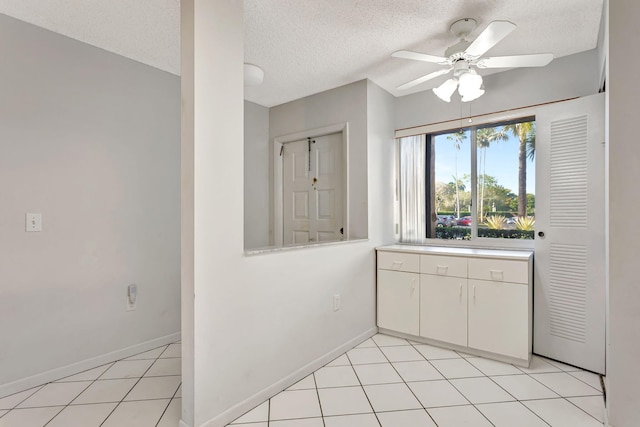 kitchen with light tile patterned flooring, a ceiling fan, baseboards, white cabinets, and light countertops