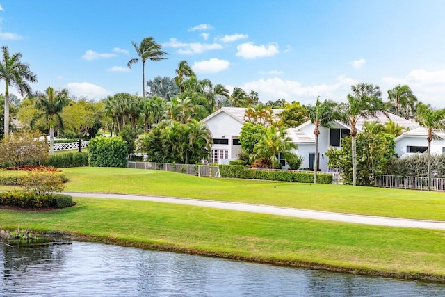 view of community with a yard, fence, and a water view