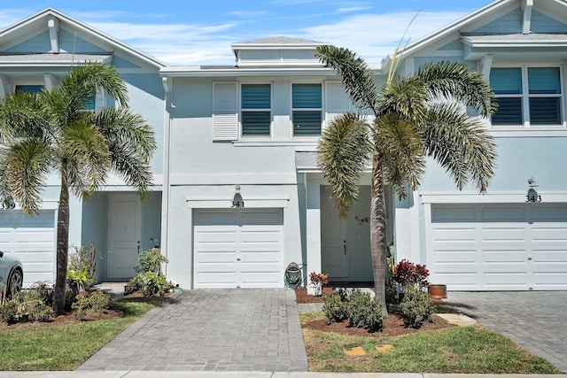 view of front of house featuring stucco siding, an attached garage, and decorative driveway