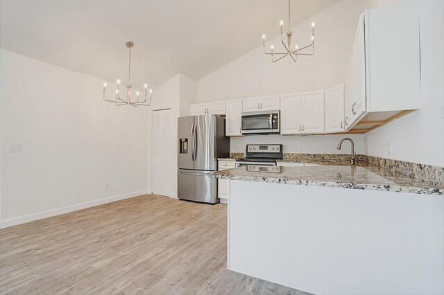 kitchen with light stone countertops, light wood-style flooring, appliances with stainless steel finishes, white cabinetry, and a notable chandelier