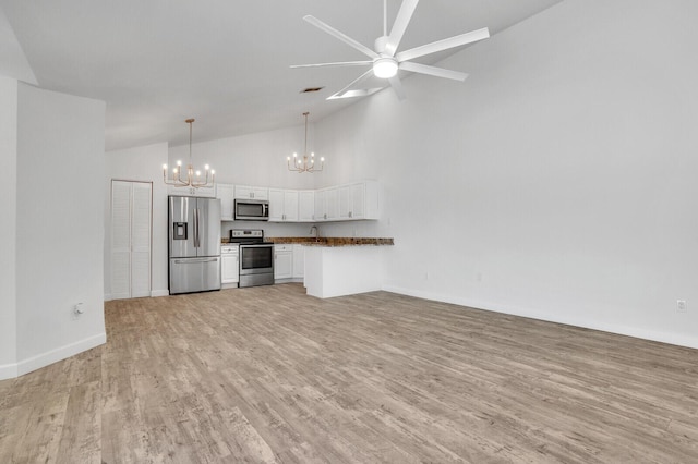 kitchen featuring dark countertops, open floor plan, appliances with stainless steel finishes, light wood-style floors, and white cabinets