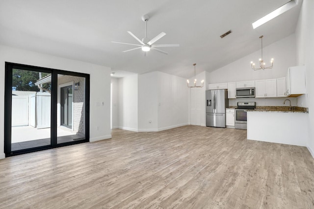 unfurnished living room with light wood finished floors, visible vents, baseboards, ceiling fan with notable chandelier, and high vaulted ceiling