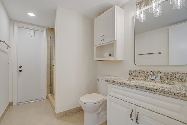 bathroom featuring toilet, a shower stall, tile patterned flooring, baseboards, and vanity