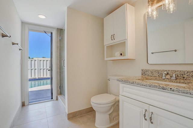 bathroom featuring tile patterned flooring, a shower stall, baseboards, toilet, and vanity