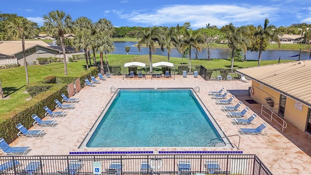 pool featuring a patio, a yard, fence, and a water view