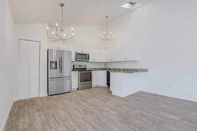 kitchen with a chandelier, appliances with stainless steel finishes, light wood-style floors, white cabinets, and a sink