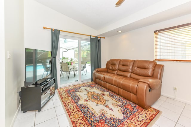 living area featuring lofted ceiling, light tile patterned floors, baseboards, and a ceiling fan