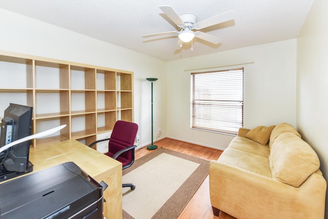 office area with a ceiling fan, a textured ceiling, baseboards, and wood finished floors