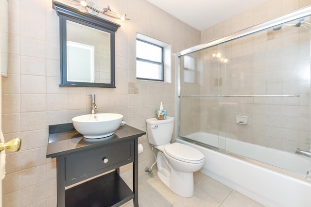 full bath with enclosed tub / shower combo, tile patterned flooring, toilet, vanity, and tile walls