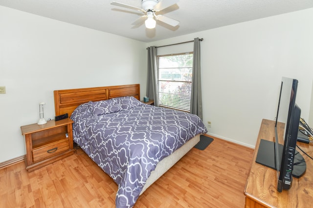 bedroom featuring a ceiling fan, a textured ceiling, baseboards, and wood finished floors