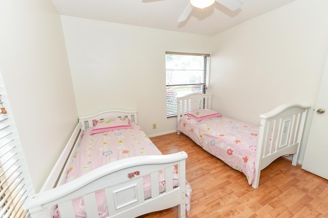 bedroom with light wood-style flooring, baseboards, and a ceiling fan