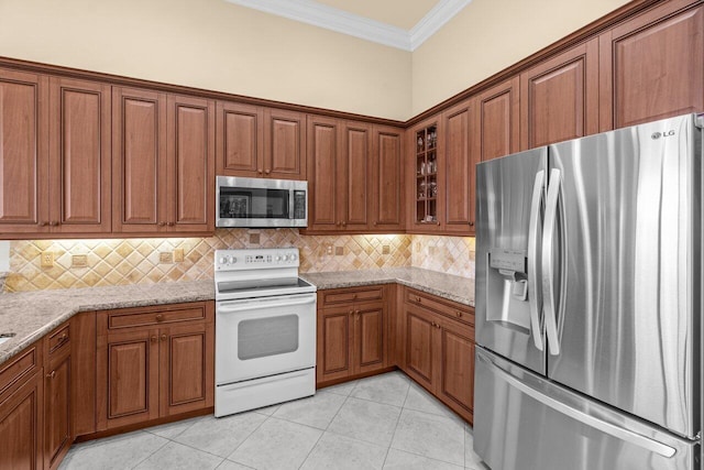 kitchen featuring brown cabinets, light tile patterned floors, tasteful backsplash, appliances with stainless steel finishes, and ornamental molding