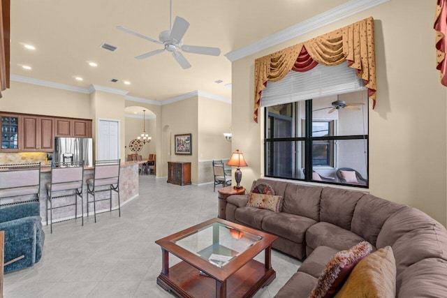 living room with light tile patterned floors, ceiling fan with notable chandelier, arched walkways, and ornamental molding