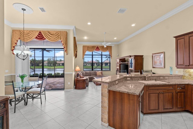 kitchen with ceiling fan with notable chandelier, crown molding, a sink, and light stone countertops