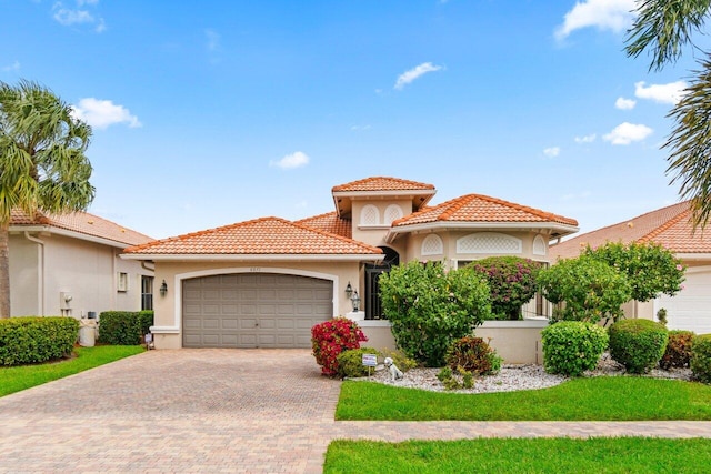 mediterranean / spanish house with an attached garage, a tiled roof, and stucco siding