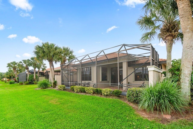 rear view of property with glass enclosure and a lawn