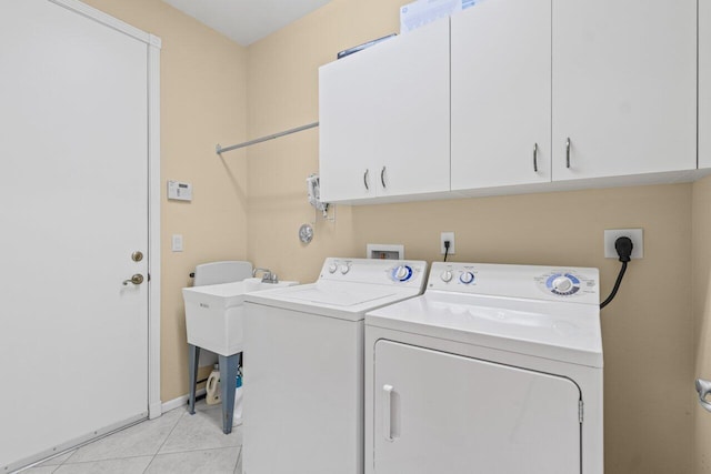 laundry area with light tile patterned floors, a sink, washing machine and dryer, and cabinet space