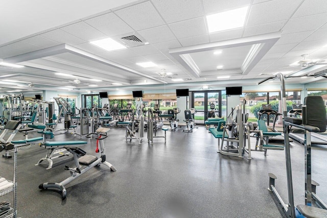 gym featuring a ceiling fan, visible vents, a raised ceiling, and crown molding