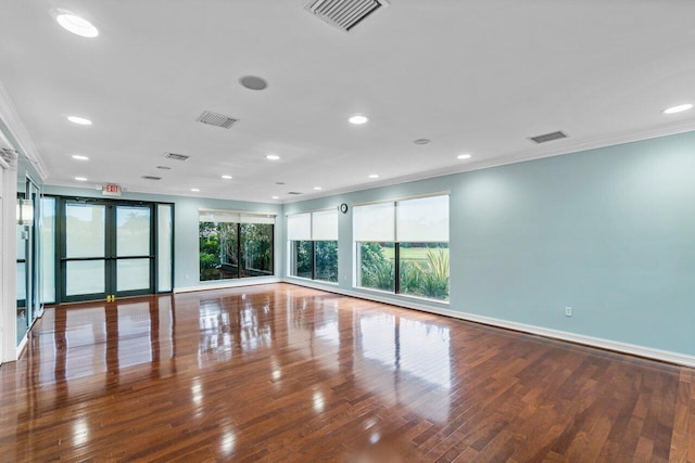 empty room featuring ornamental molding, wood-type flooring, visible vents, and baseboards