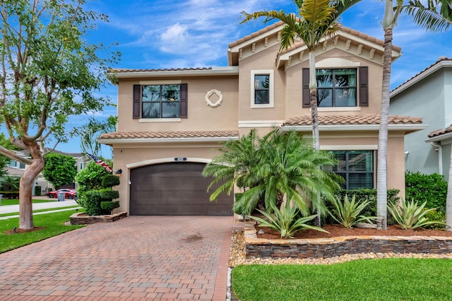 view of front of house with a tiled roof, decorative driveway, an attached garage, and stucco siding