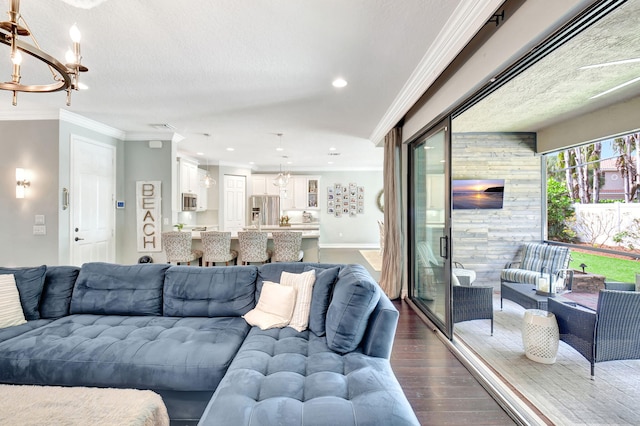 living area featuring dark wood finished floors, recessed lighting, an inviting chandelier, ornamental molding, and a textured ceiling