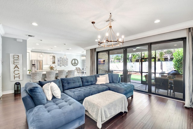 living area with visible vents, dark wood-style floors, an inviting chandelier, a textured ceiling, and crown molding