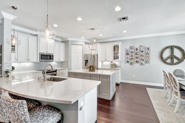 kitchen with visible vents, appliances with stainless steel finishes, a center island, a peninsula, and a sink