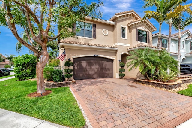 mediterranean / spanish-style home featuring a tiled roof, decorative driveway, and stucco siding