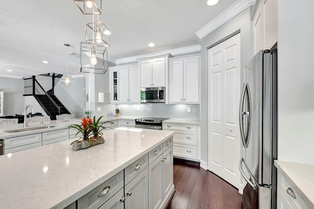 kitchen featuring appliances with stainless steel finishes, crown molding, a sink, and light stone counters