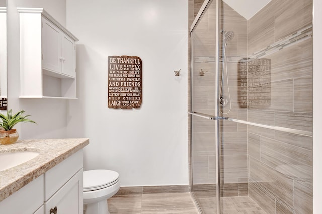 full bathroom with a stall shower, vanity, and toilet