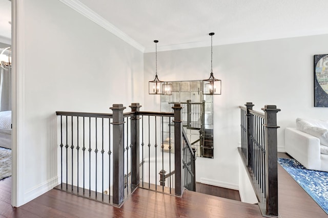 staircase featuring baseboards, crown molding, a chandelier, and wood finished floors