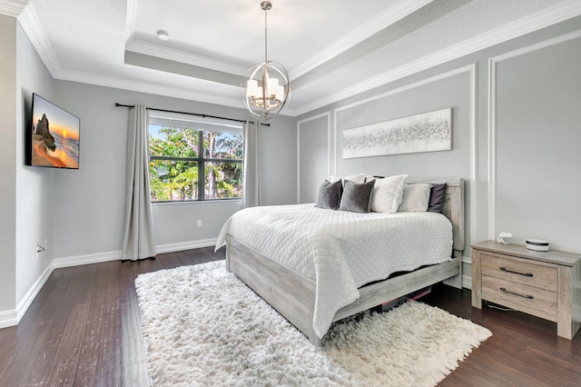 bedroom featuring baseboards, a raised ceiling, dark wood-style floors, crown molding, and a notable chandelier