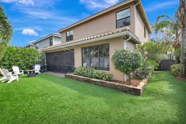 rear view of house featuring a sunroom, stucco siding, a lawn, and fence