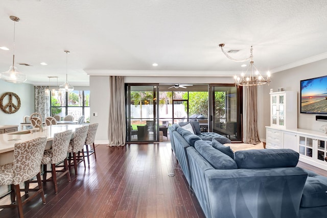 living room featuring an inviting chandelier, baseboards, ornamental molding, and dark wood finished floors