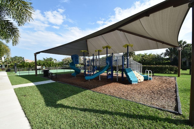 community jungle gym featuring a lawn and fence