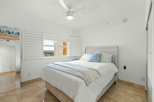 bedroom featuring a ceiling fan, baseboards, and arched walkways