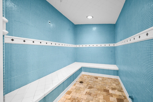 bathroom featuring tiled shower and tile walls