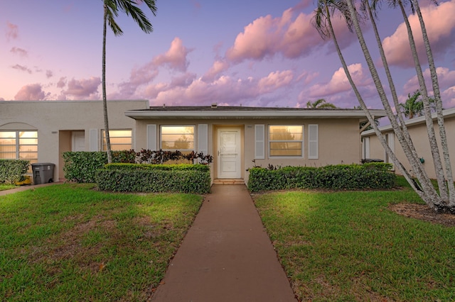 view of front of house featuring stucco siding and a front yard