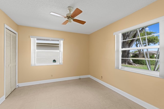 unfurnished bedroom featuring multiple windows, baseboards, and a textured ceiling