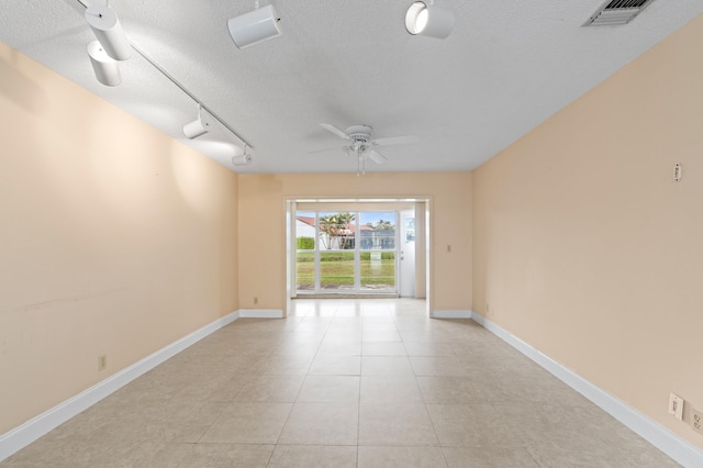 empty room featuring light tile patterned floors, baseboards, visible vents, ceiling fan, and a textured ceiling