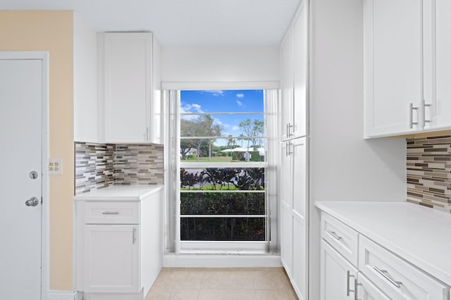 kitchen featuring white cabinetry, light countertops, light tile patterned flooring, and backsplash