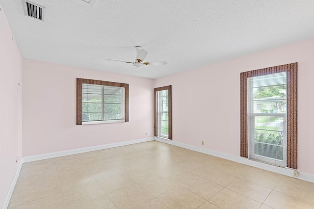 empty room featuring a textured ceiling, baseboards, visible vents, and ceiling fan