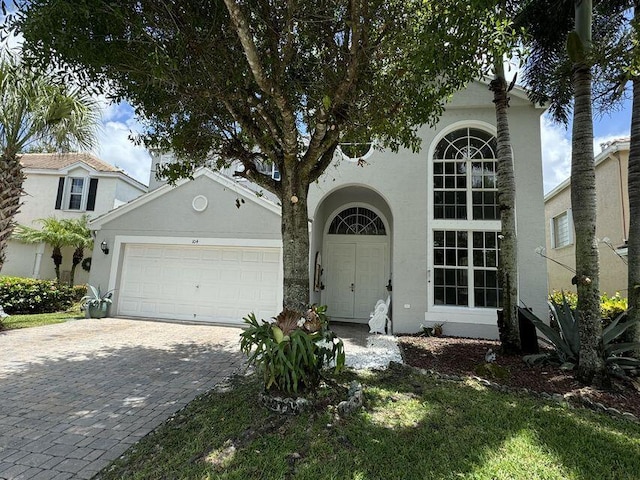 view of front of home with an attached garage, decorative driveway, and stucco siding