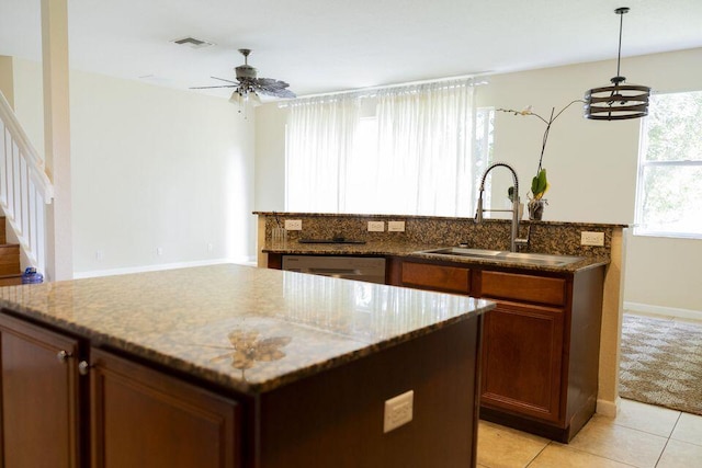 kitchen featuring stone counters, a center island, visible vents, and a sink