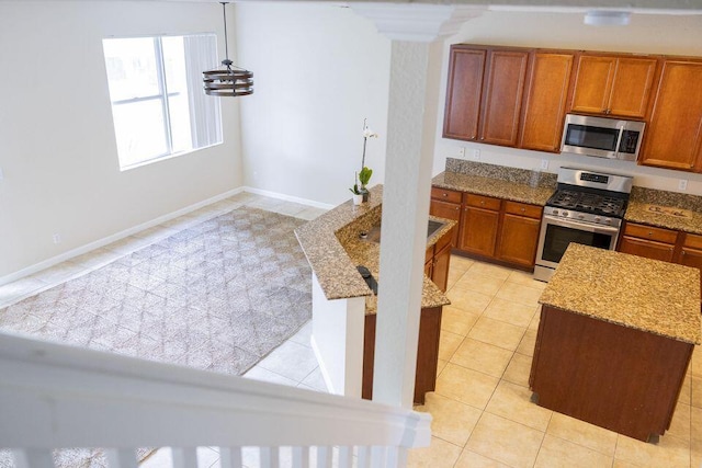 kitchen featuring appliances with stainless steel finishes, brown cabinets, light stone counters, and light tile patterned floors