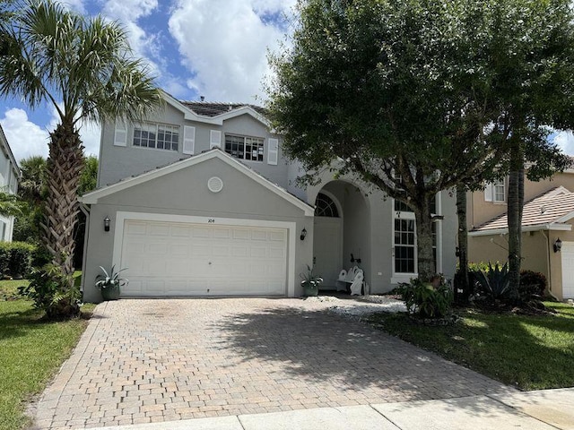 view of front facade featuring decorative driveway, an attached garage, and stucco siding