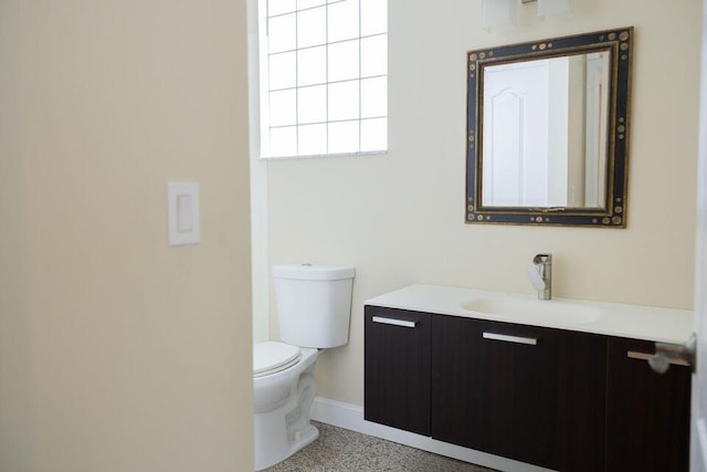 bathroom featuring toilet, speckled floor, vanity, and baseboards