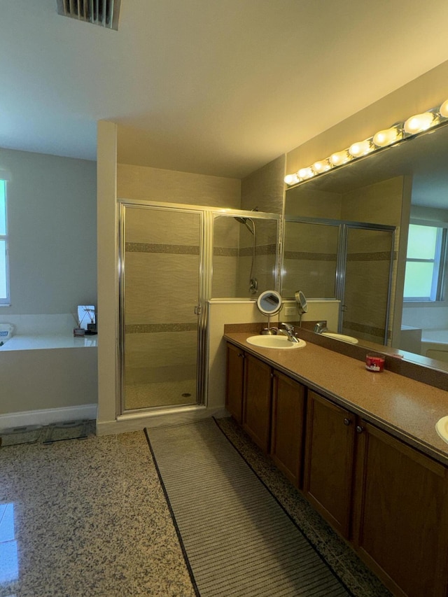 full bath featuring visible vents, a sink, a shower stall, and double vanity