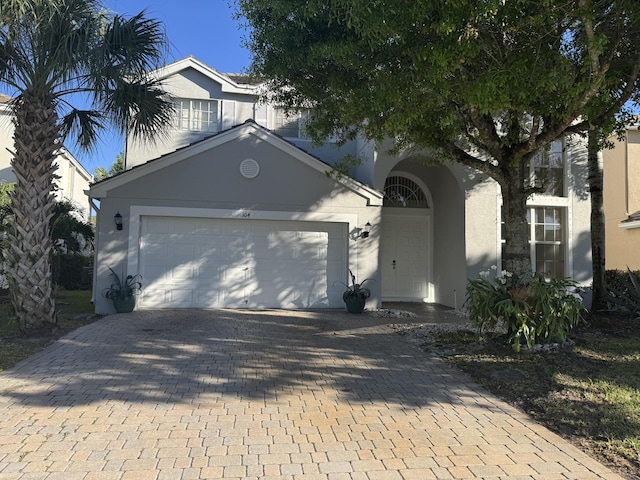 view of front of property with decorative driveway, an attached garage, and stucco siding